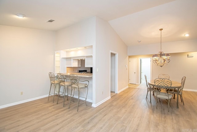 dining space with light hardwood / wood-style flooring, a notable chandelier, and lofted ceiling