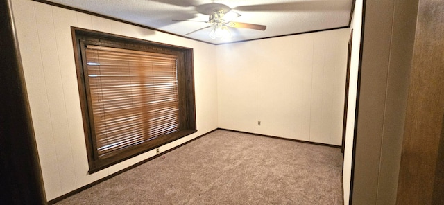 spare room with light carpet, ceiling fan, ornamental molding, and wooden walls