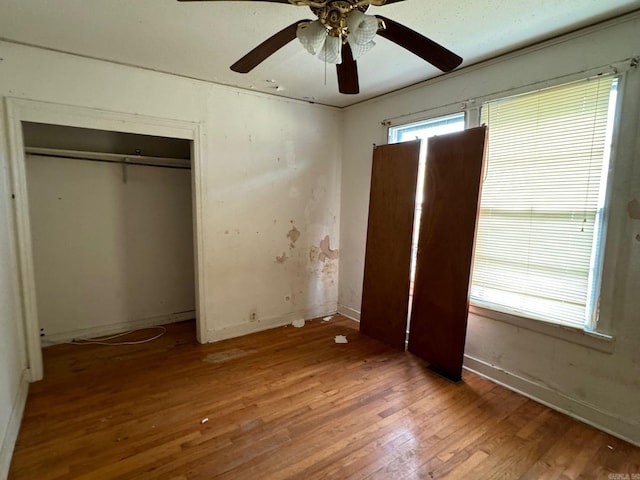 unfurnished bedroom with ceiling fan, a closet, and hardwood / wood-style floors