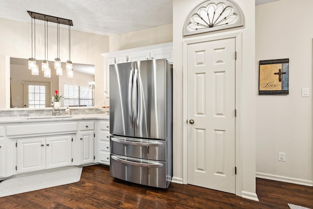 kitchen with white cabinetry, dark wood-type flooring, stainless steel refrigerator, and decorative light fixtures