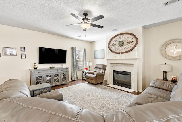 living room featuring hardwood / wood-style flooring, ceiling fan, a high end fireplace, and a textured ceiling