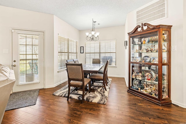 dining space with a textured ceiling, dark wood-type flooring, and an inviting chandelier