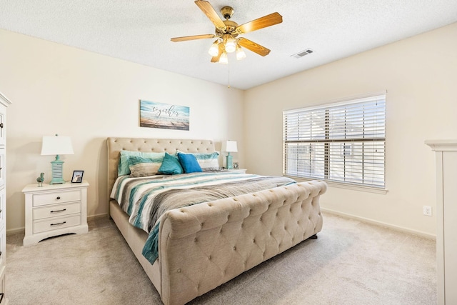 bedroom with a textured ceiling, ceiling fan, and light colored carpet