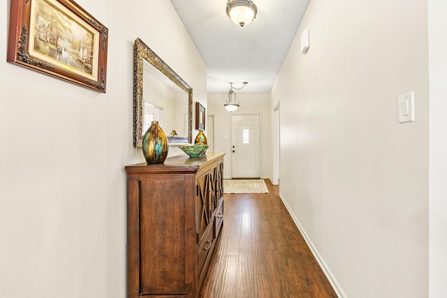 hall with dark wood-type flooring and a textured ceiling