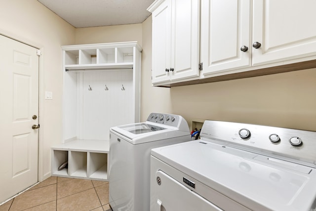 washroom with cabinets, light tile patterned floors, and washer and clothes dryer