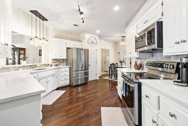 kitchen featuring tasteful backsplash, hanging light fixtures, stainless steel appliances, sink, and white cabinetry