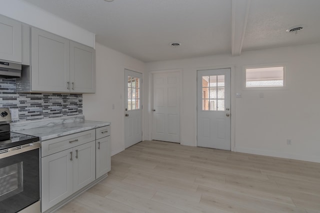 kitchen featuring light stone countertops, light hardwood / wood-style floors, range hood, stainless steel electric stove, and decorative backsplash