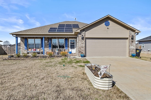 view of front of home featuring a garage, solar panels, a front yard, and a porch