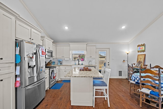 kitchen with white cabinetry, a center island, ornamental molding, light stone counters, and appliances with stainless steel finishes