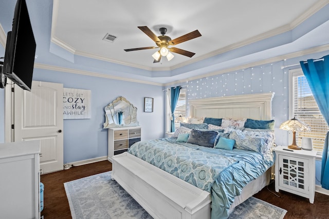 bedroom with dark hardwood / wood-style floors, ceiling fan, a tray ceiling, and ornamental molding