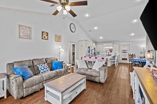 living room with ceiling fan, vaulted ceiling, dark wood-type flooring, and ornamental molding