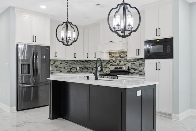 kitchen featuring a notable chandelier, stainless steel appliances, white cabinetry, and an island with sink