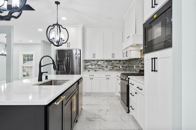 kitchen with appliances with stainless steel finishes, hanging light fixtures, sink, white cabinetry, and a kitchen island with sink