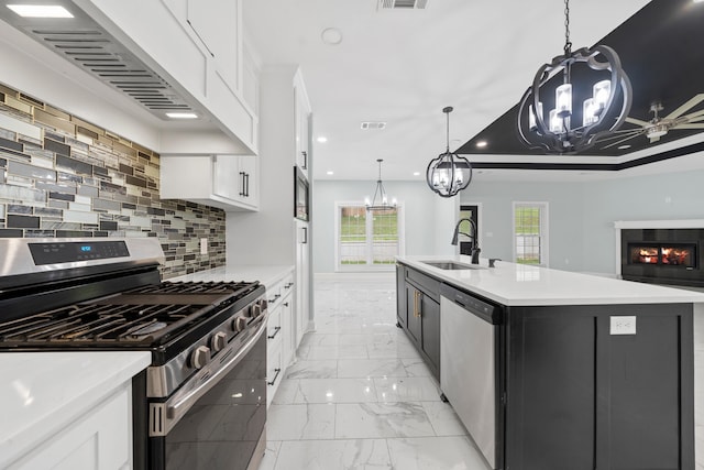 kitchen with premium range hood, stainless steel appliances, an island with sink, white cabinets, and sink