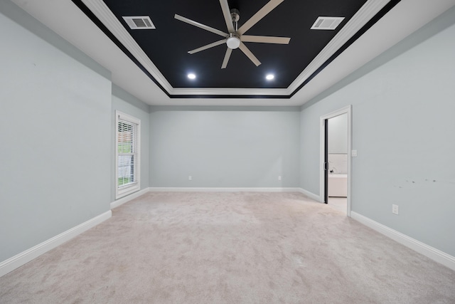 unfurnished room featuring a raised ceiling, crown molding, light carpet, and ceiling fan