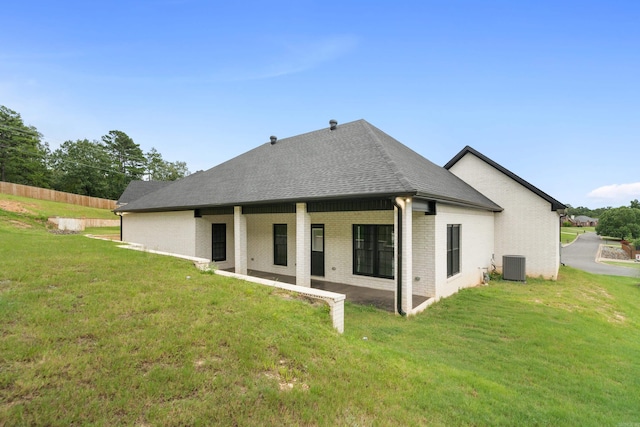 back of property with cooling unit, a lawn, and a patio area