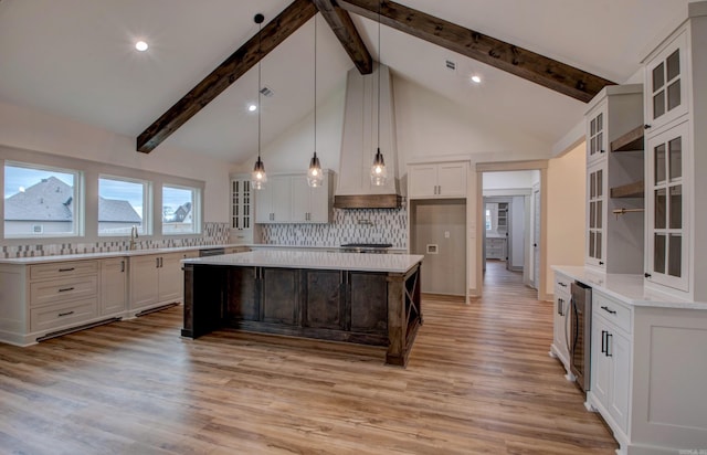 kitchen with beam ceiling, light hardwood / wood-style flooring, white cabinets, decorative backsplash, and a kitchen island