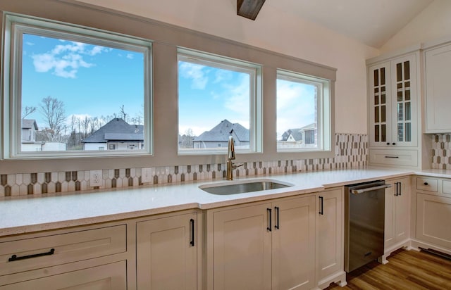 kitchen featuring lofted ceiling, sink, light hardwood / wood-style floors, stainless steel dishwasher, and decorative backsplash