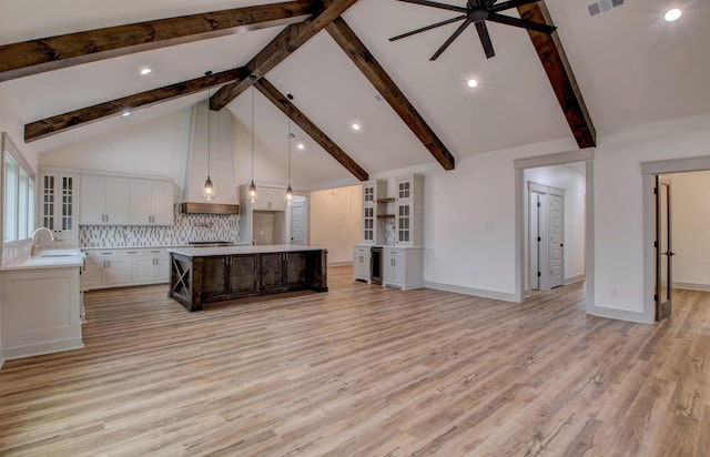 kitchen featuring sink, backsplash, white cabinetry, pendant lighting, and a kitchen island