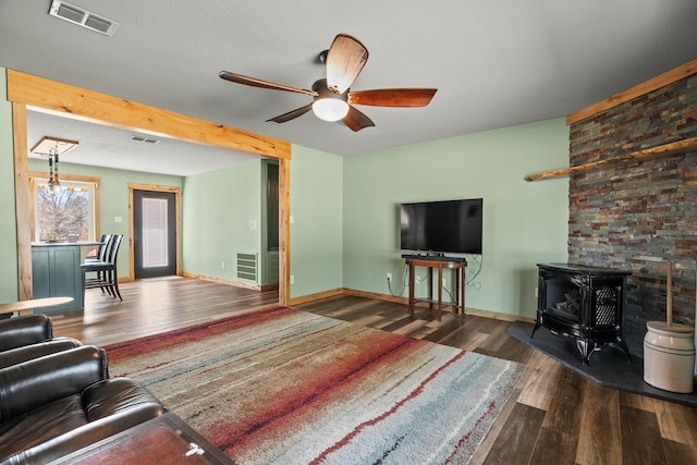 living room featuring a wood stove, dark hardwood / wood-style floors, and ceiling fan