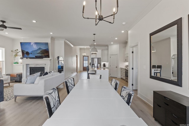 dining room featuring ceiling fan with notable chandelier, light wood-type flooring, and crown molding