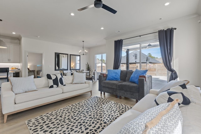 living room featuring ceiling fan with notable chandelier, light wood-type flooring, and ornamental molding