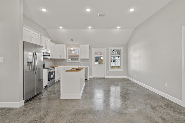 kitchen featuring appliances with stainless steel finishes, vaulted ceiling, pendant lighting, white cabinets, and concrete flooring