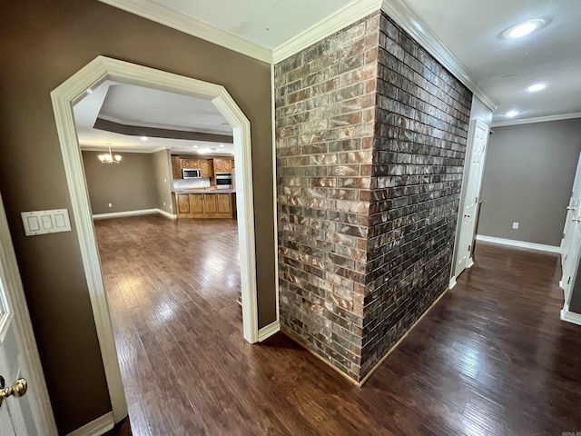 hall featuring dark wood-type flooring, brick wall, and ornamental molding