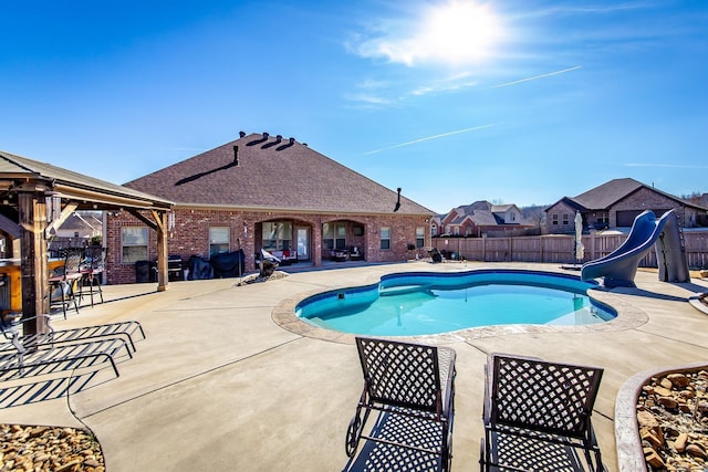 view of swimming pool featuring a patio, a gazebo, and a water slide