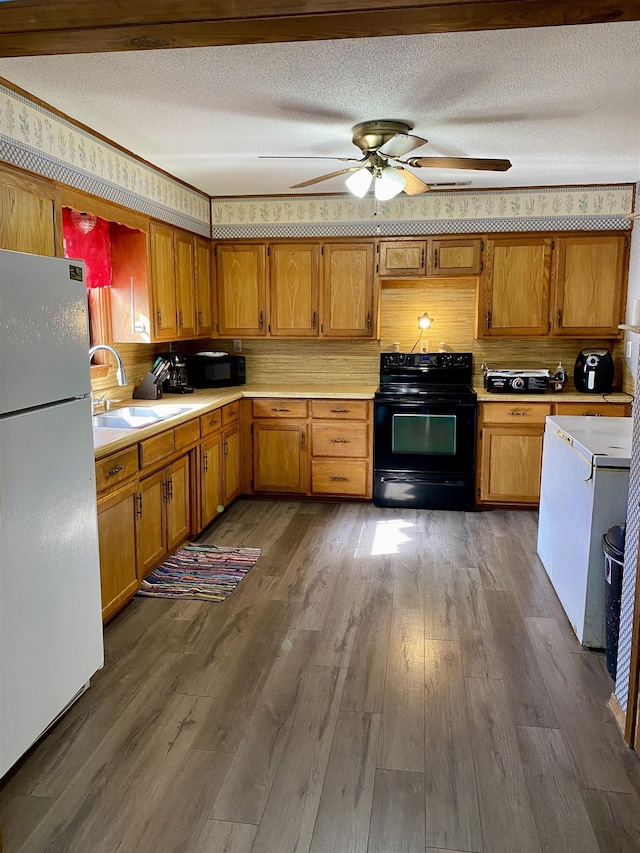 kitchen with dark hardwood / wood-style flooring, black appliances, sink, ceiling fan, and a textured ceiling