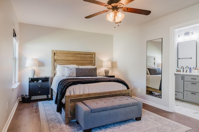 bedroom with ensuite bathroom, light hardwood / wood-style flooring, and ceiling fan