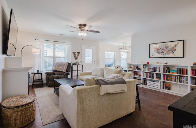 living room with ceiling fan with notable chandelier and hardwood / wood-style floors