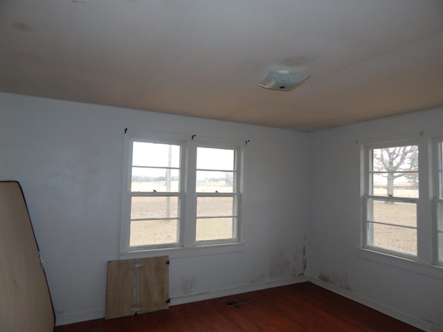 empty room featuring plenty of natural light and dark wood-type flooring