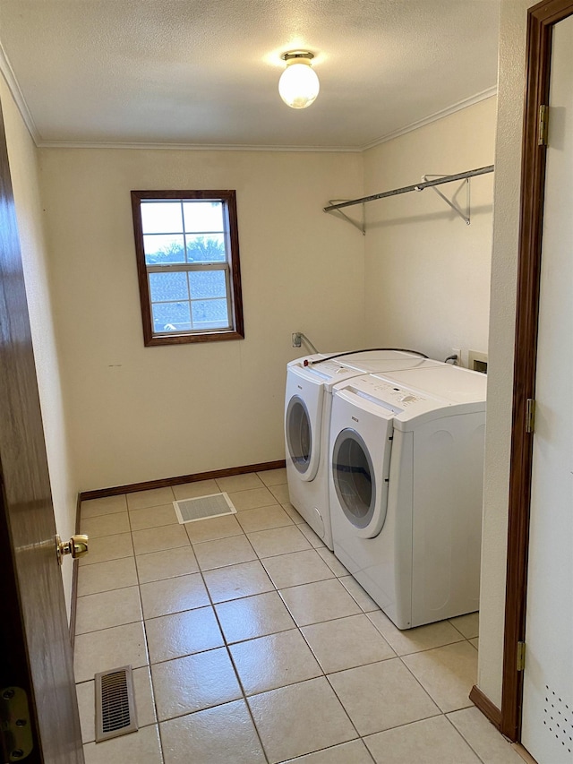 laundry room featuring light tile patterned floors, separate washer and dryer, and a textured ceiling