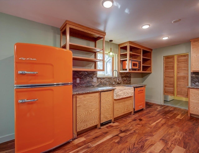 kitchen with sink, dark wood-type flooring, fridge, and decorative light fixtures