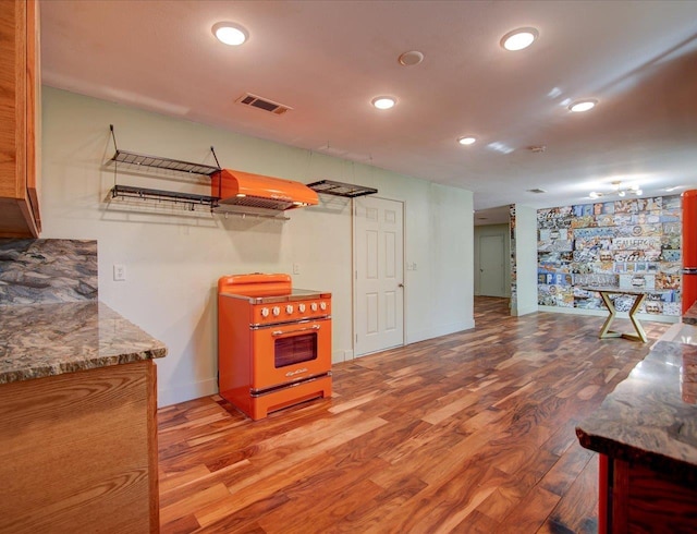 kitchen featuring island range hood, stone counters, range, and light hardwood / wood-style flooring