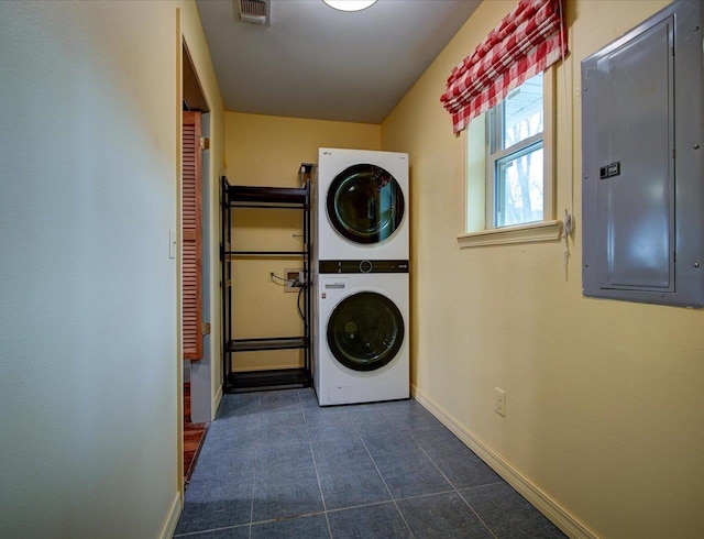 clothes washing area featuring electric panel and stacked washing maching and dryer