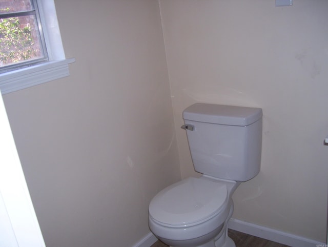 bathroom with baseboards, toilet, and wood finished floors