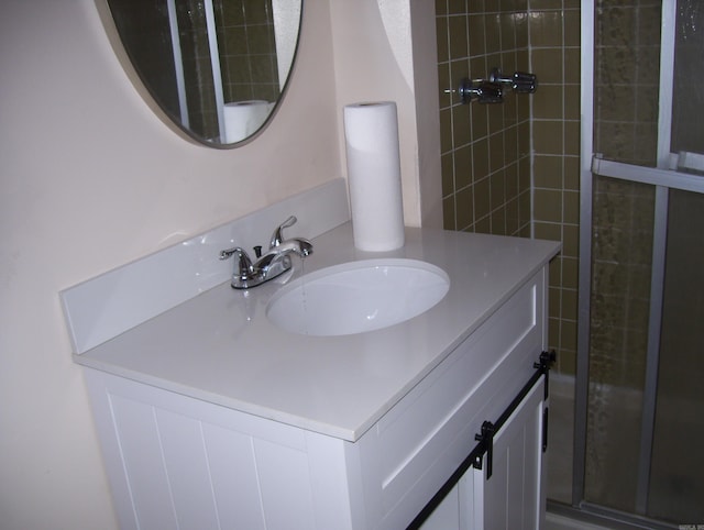 full bathroom featuring tiled shower and vanity