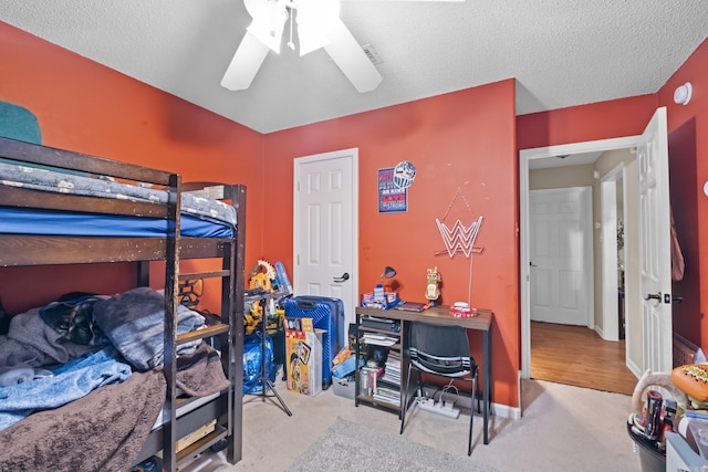 bedroom with light colored carpet, ceiling fan, and a textured ceiling