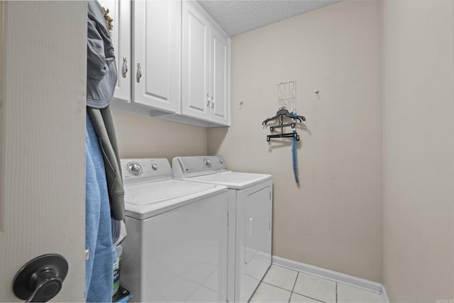 laundry area featuring cabinets, light tile patterned floors, separate washer and dryer, and a textured ceiling