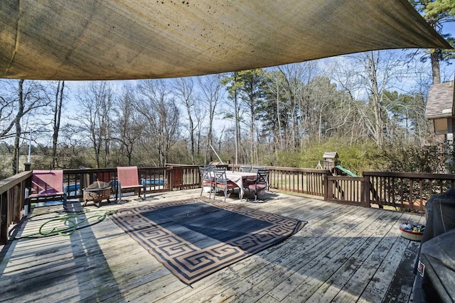 wooden terrace featuring a playground and an outdoor fire pit