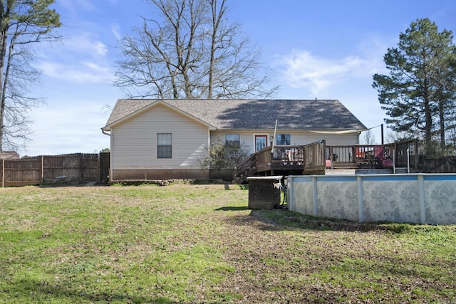 rear view of house with a swimming pool side deck and a lawn