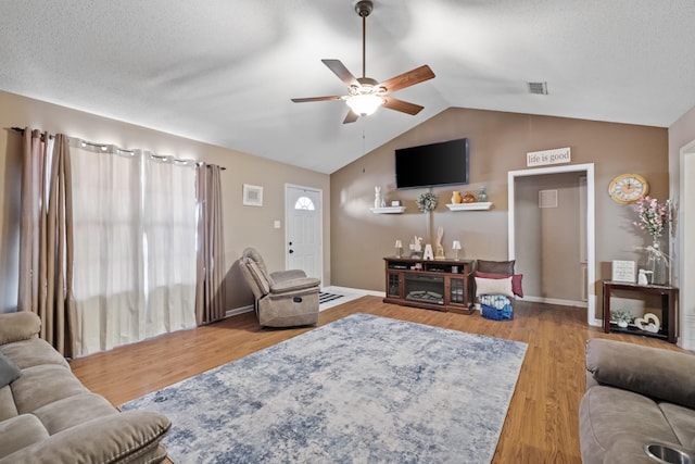 living room featuring ceiling fan, light hardwood / wood-style floors, vaulted ceiling, and a textured ceiling