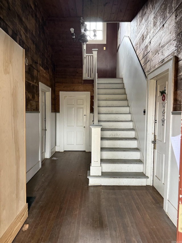 staircase featuring wood-type flooring, wood ceiling, and wooden walls