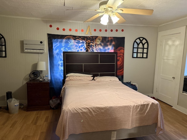 bedroom with ornamental molding, hardwood / wood-style flooring, and a wall mounted air conditioner