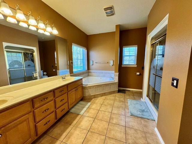 bathroom with tile patterned floors, a wealth of natural light, independent shower and bath, and vanity