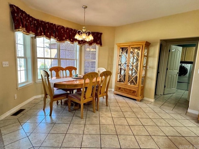 tiled dining room featuring washer / clothes dryer and a chandelier