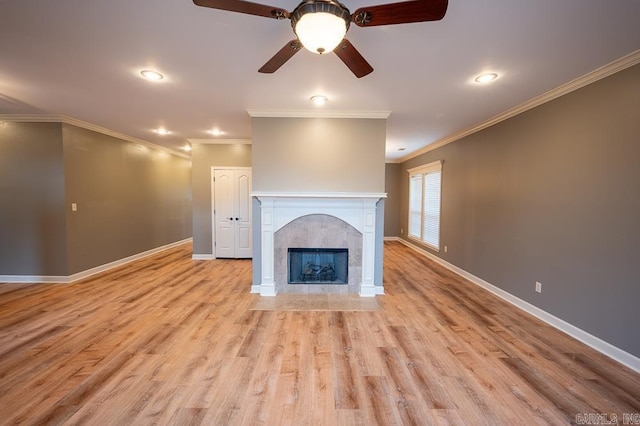 unfurnished living room featuring a fireplace, crown molding, light wood-type flooring, and ceiling fan