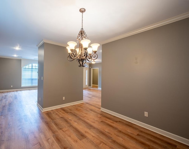 unfurnished room with ornamental molding, light hardwood / wood-style floors, and an inviting chandelier